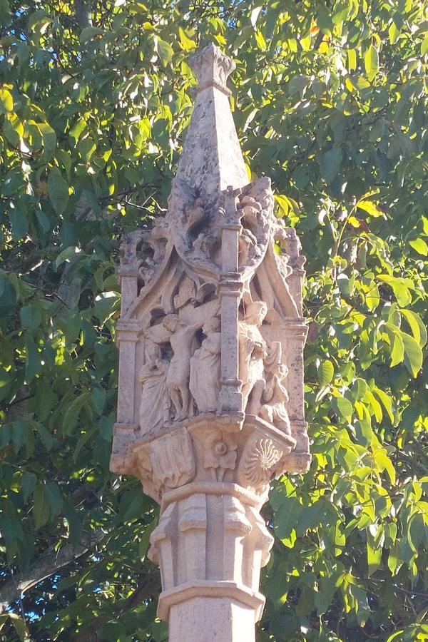 The carved head of the cross from another side, against a pale sky.