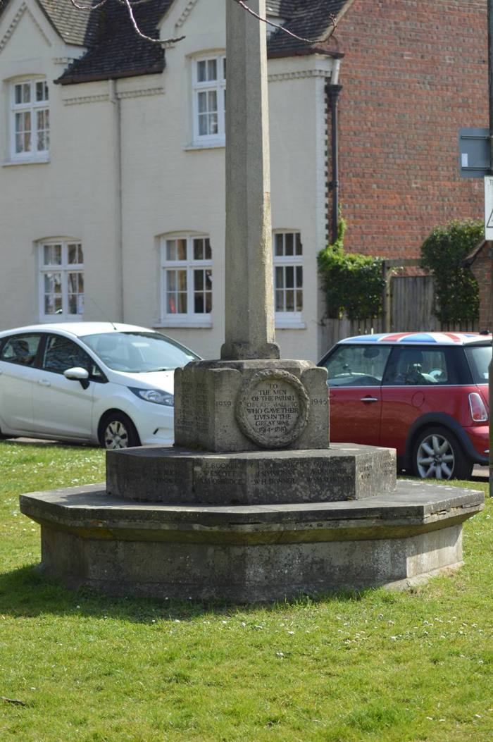 The memorial cross on its stepped octagonal base, standing on the green.